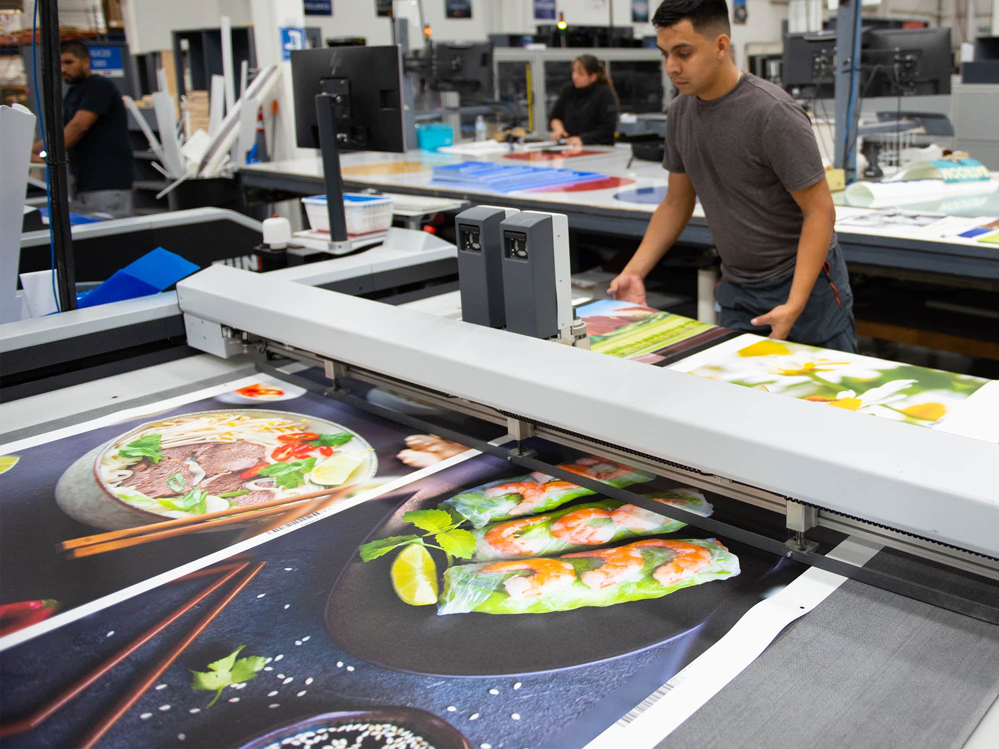 Worker pulls canvas prints off a machine